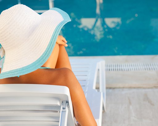 Young woman sunbathing at the edge of swimming pool.